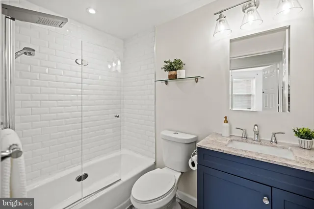 a bathroom with a granite countertop sink a toilet and shower