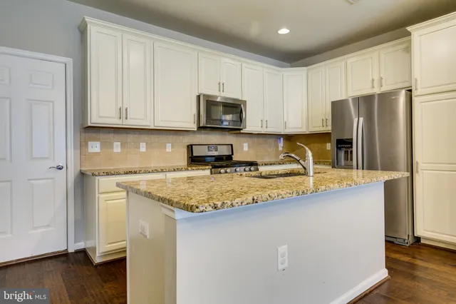 a kitchen with stainless steel appliances granite countertop a refrigerator a stove a sink a microwave and cabinets