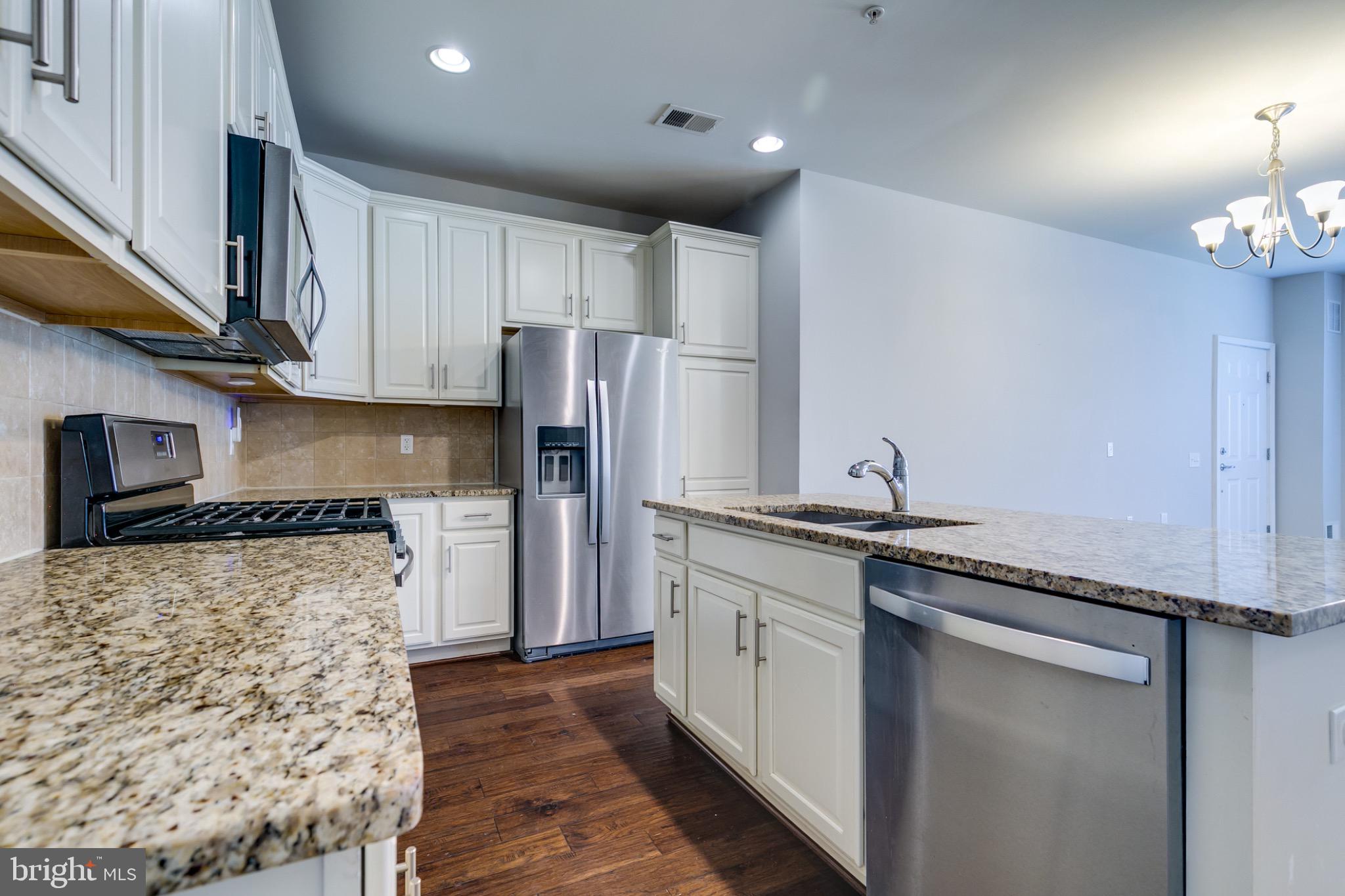20581 Geddes Terrace Ashburn, VA 20147 - Photo 12 of 37 a kitchen with stainless steel appliances granite countertop a refrigerator a oven and white cabinets with wooden floors