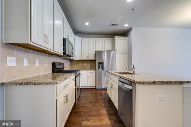 a kitchen with granite countertop stainless steel appliances and white cabinets