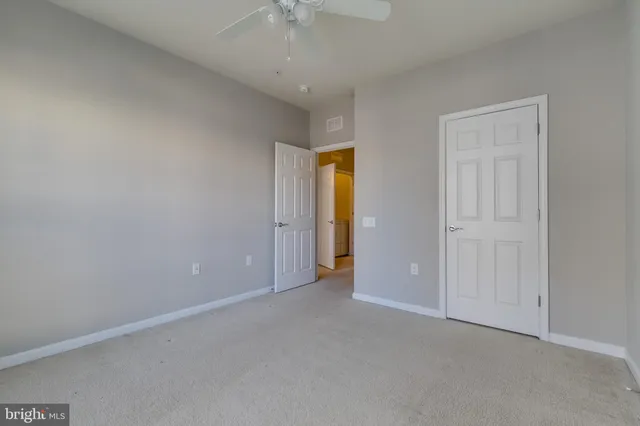 an empty room with closet and a chandelier fan