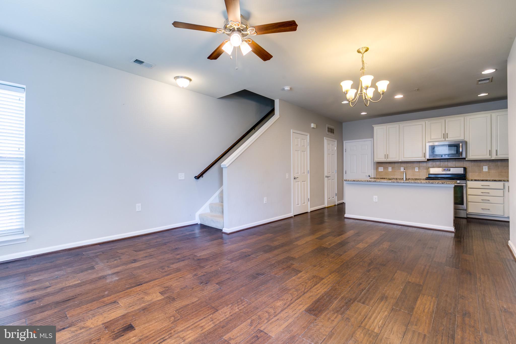20581 Geddes Terrace Ashburn, VA 20147 - Photo 4 of 37 an empty room with wooden floor ceiling fan and kitchen view