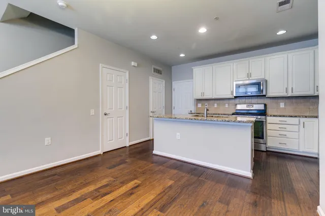 a kitchen with granite countertop wooden floors stainless steel appliances and cabinets