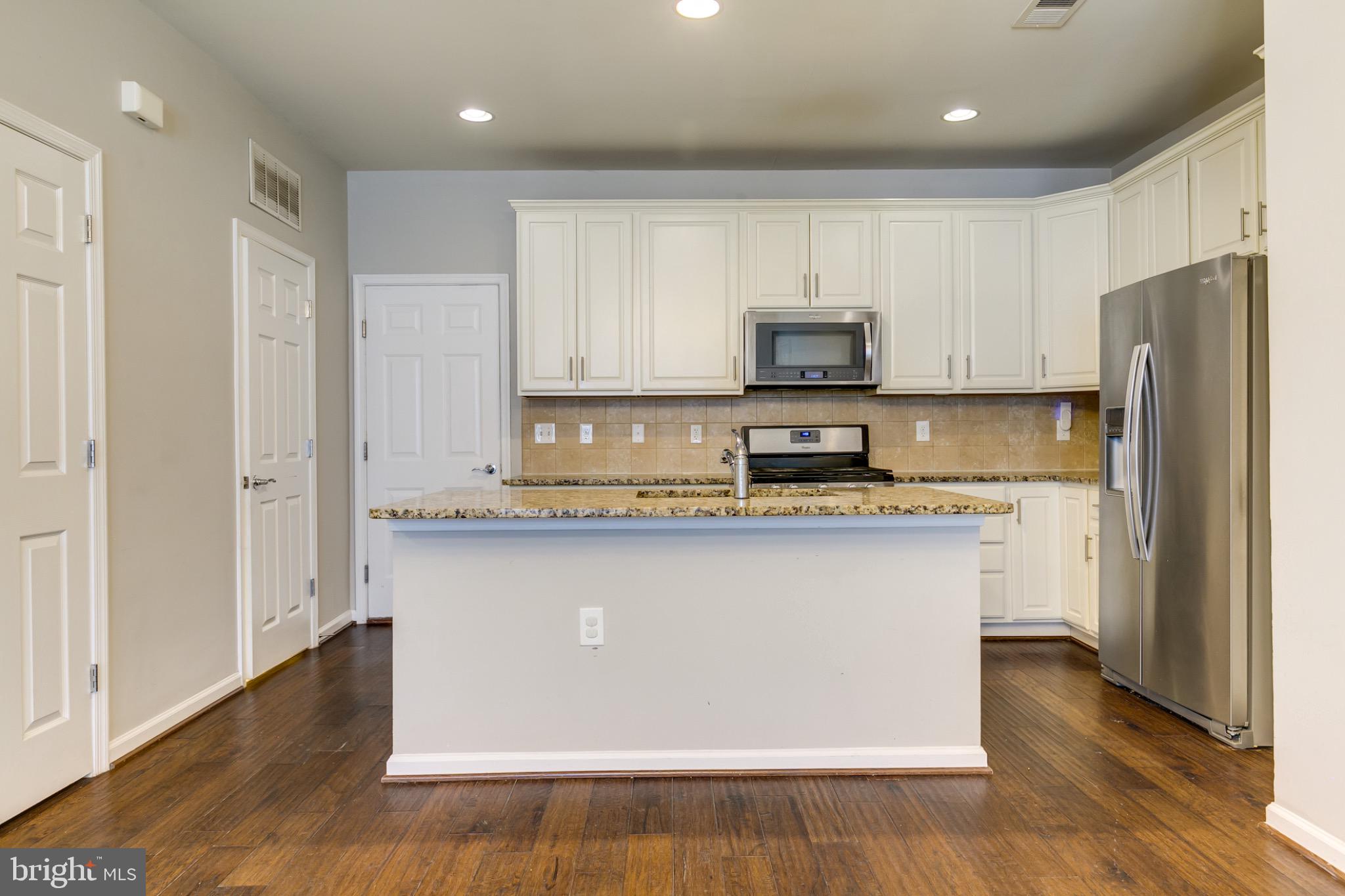 20581 Geddes Terrace Ashburn, VA 20147 - Photo 10 of 37 a kitchen with stainless steel appliances granite countertop a refrigerator a stove a sink and white cabinets with wooden floor