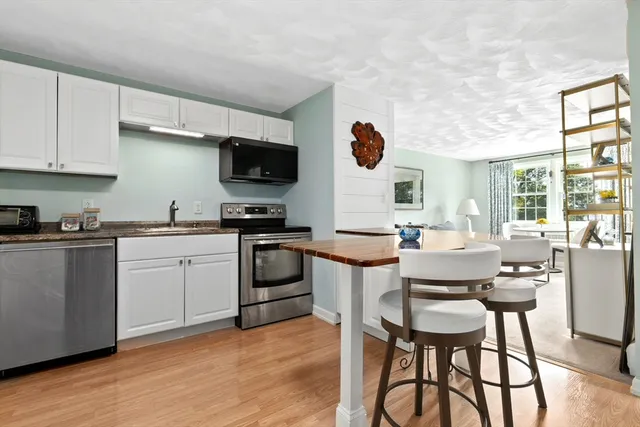 a kitchen with a table chairs a sink dishwasher stove and cabinets with wooden floor