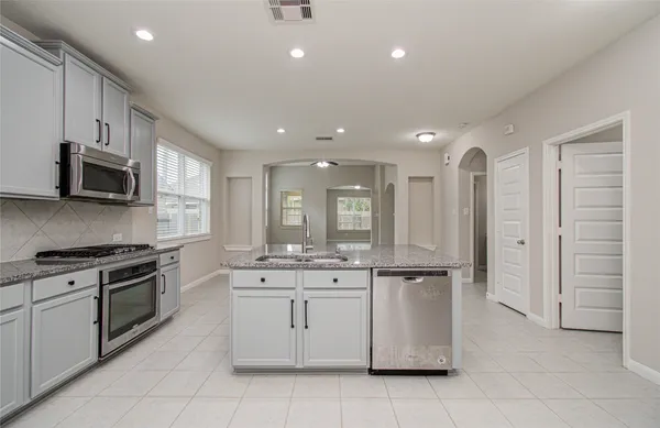 a kitchen with granite countertop white cabinets and stainless steel appliances