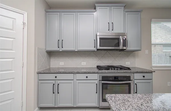 a kitchen with granite countertop white cabinets stainless steel appliances and a sink