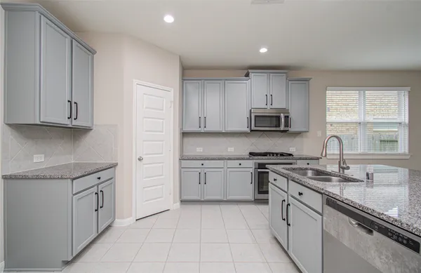 a large kitchen with stainless steel appliances granite countertop a large window
