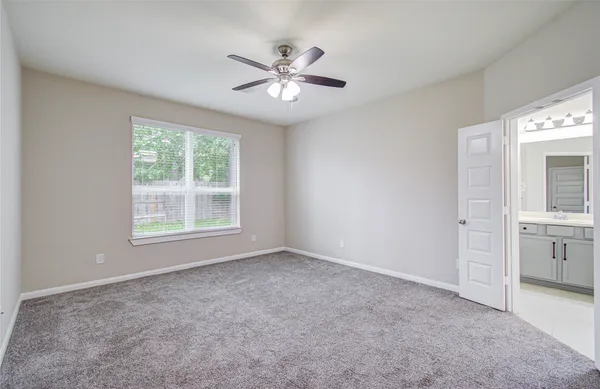 an empty room with windows and fan