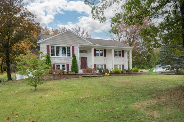 a front view of a house with a garden and trees