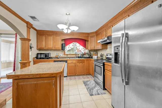 a kitchen with granite countertop stainless steel appliances a sink cabinets and a window