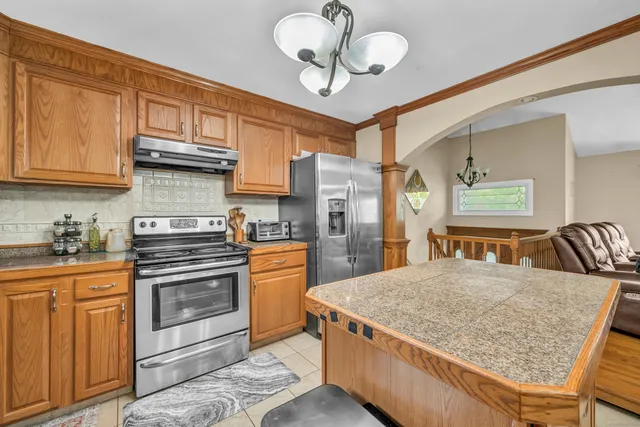 a kitchen with stainless steel appliances granite countertop a stove a sink dishwasher and a refrigerator with wooden cabinets