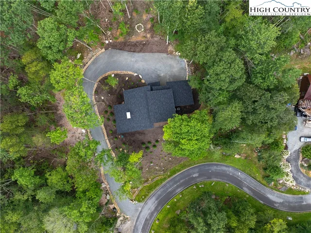 an aerial view of a house with a yard and large trees