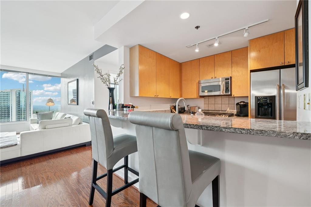3338 Peachtree Road Northeast, Unit 3006 Atlanta, GA 30326 - Photo 12 of 35 a kitchen with stainless steel appliances granite countertop sink microwave and wooden floor