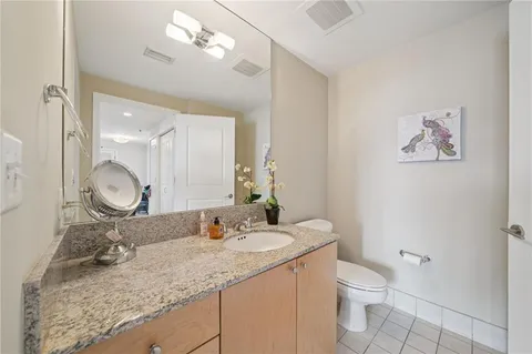 a bathroom with a granite countertop sink a toilet and a mirror