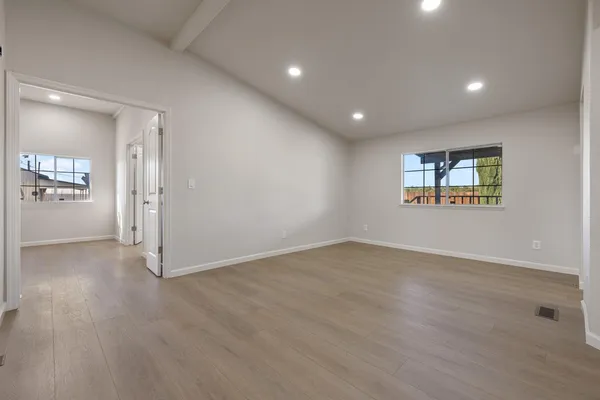 an empty room with wooden floor and windows