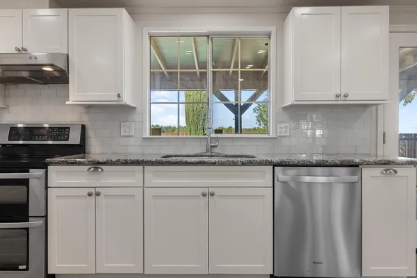 a kitchen with granite countertop white cabinets and white appliances