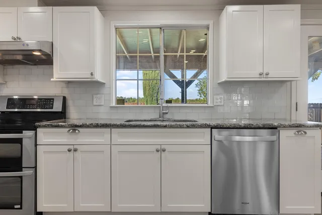 a kitchen with granite countertop white cabinets and white appliances