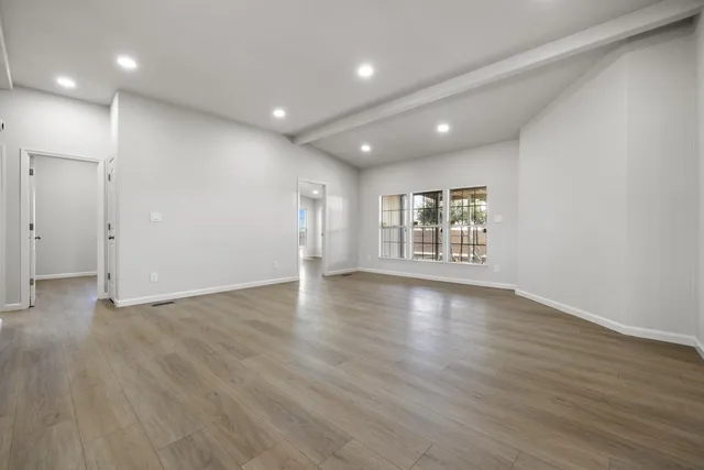 a view of a big room with wooden floor kitchen and windows