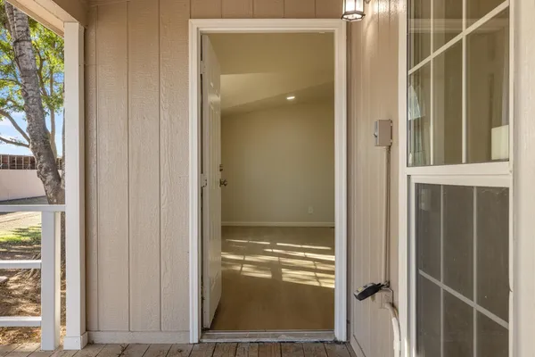 an empty room with wooden floor and a hallway