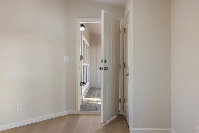 a view of an empty room with window and wooden floor