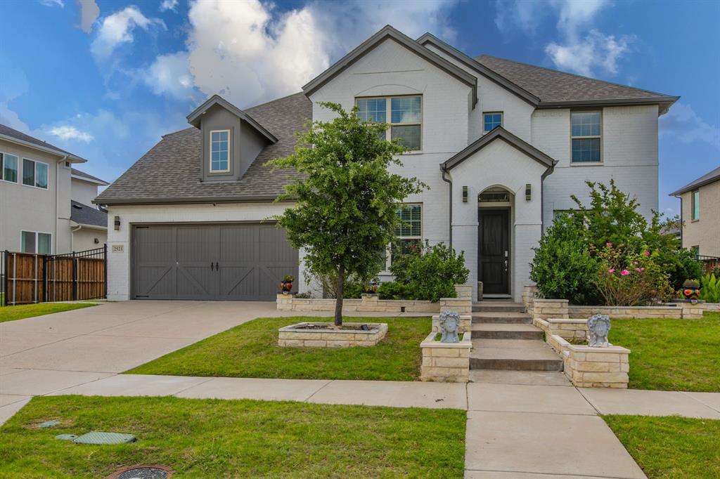 Stately two-story residence featuring a white brick exterior, dark-trimmed windows, and a prominent front entry with an overhead dormer