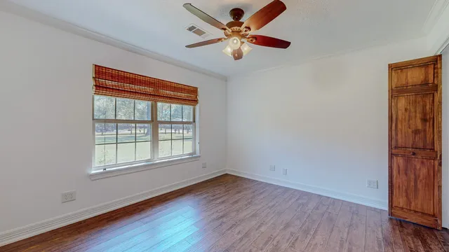 an empty room with wooden floor fan and windows