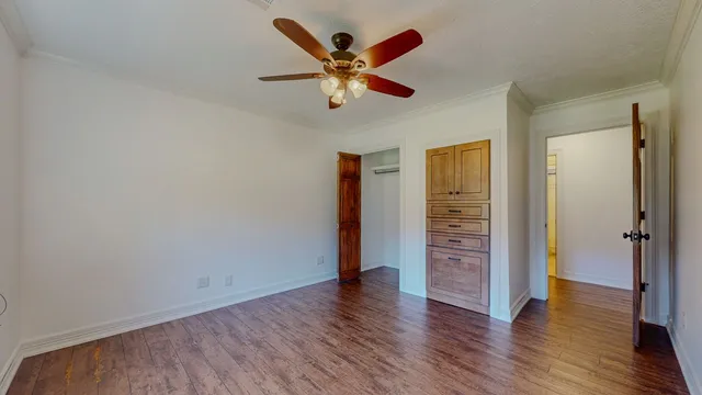 an empty room with wooden floor and ceiling fan