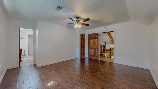 an empty room with wooden floor ceiling fan and windows