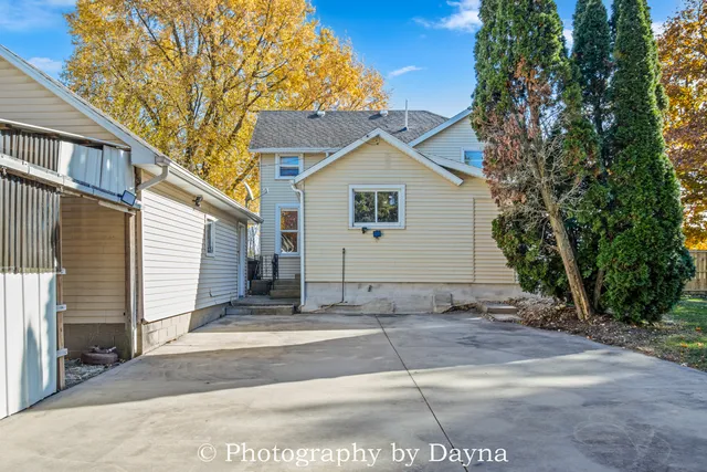 a view of a white house with a large tree