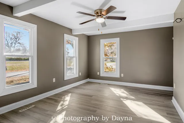 a view of an empty room with window and chandelier fan