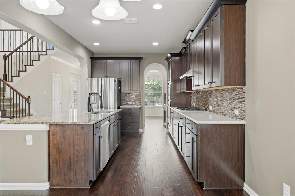12809 Spring Hill Drive Frisco, TX 75035 - Photo 13 of 37 a kitchen with stainless steel appliances granite countertop a refrigerator a stove and a wooden floors