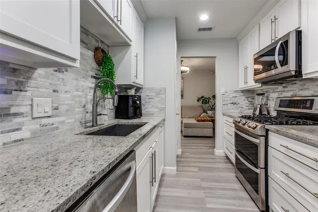 a kitchen with stainless steel appliances granite countertop a stove top oven a sink and dishwasher