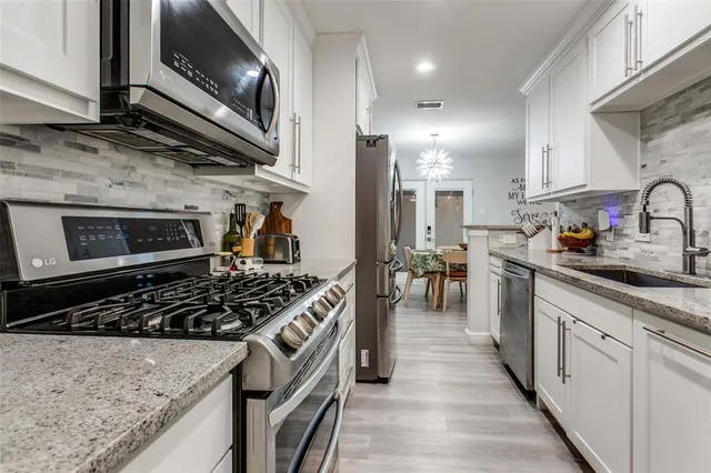 a kitchen with stainless steel appliances granite countertop a stove a sink and a microwave