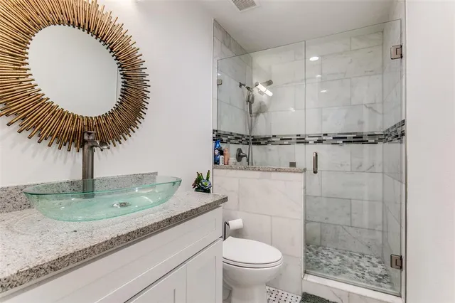 a bathroom with a granite countertop sink mirror vanity and toilet