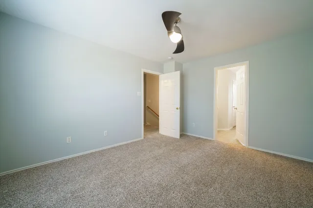 a view of an empty room with a chandelier fan