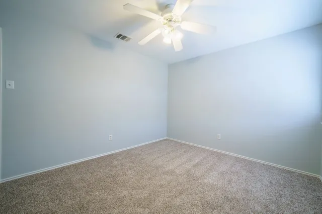an empty room with a fan and a ceiling fan