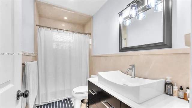 a bathroom with a sink a toilet a mirror and shower