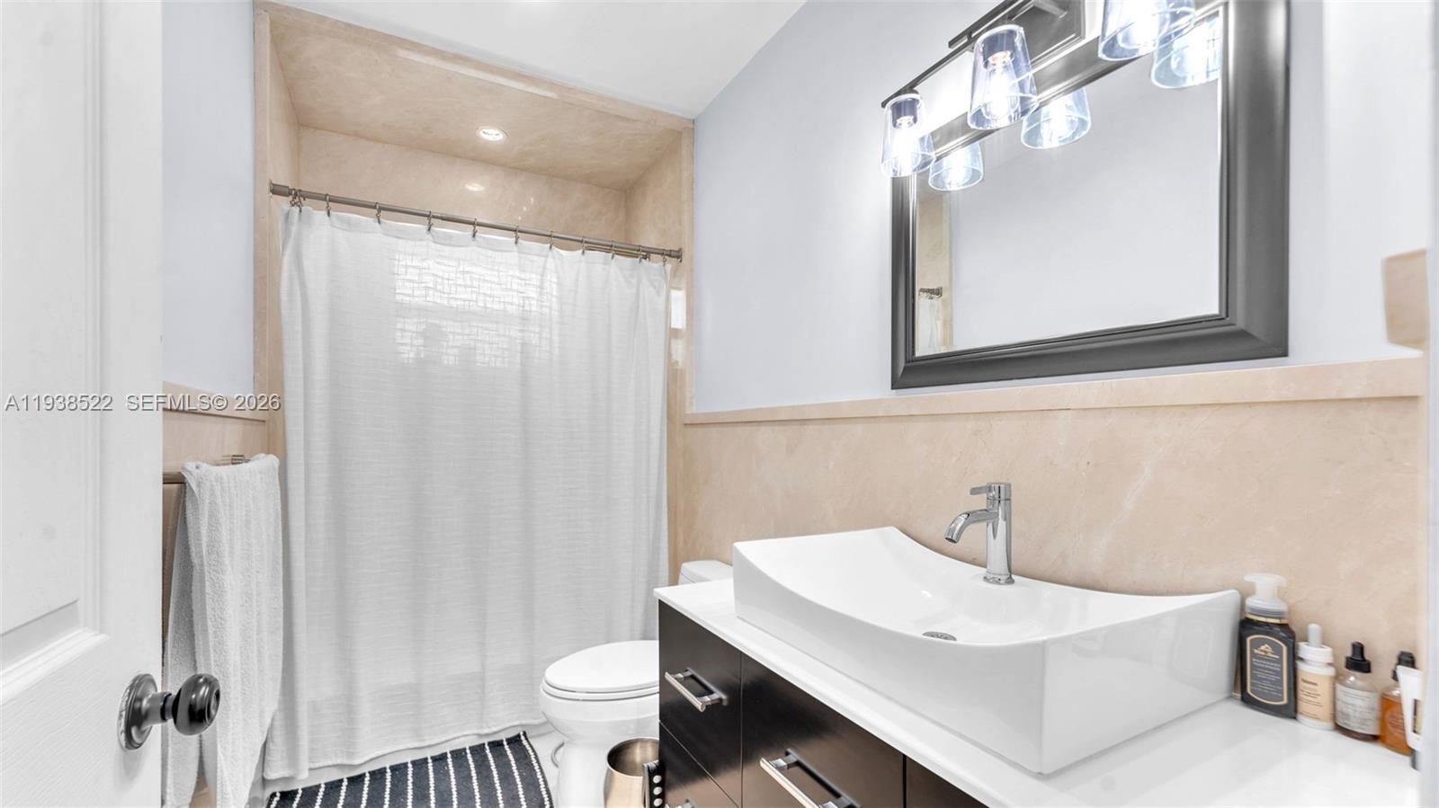 8261 Southwest 27th Street Miami, FL 33155 - Photo 7 of 27 a bathroom with a sink a toilet a mirror and shower