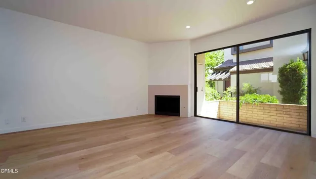 a view of empty room with wooden floor and fireplace