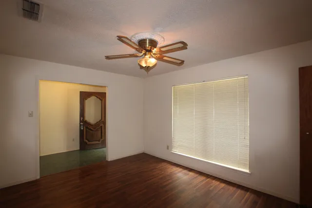 a view of an empty room with window and wooden floor