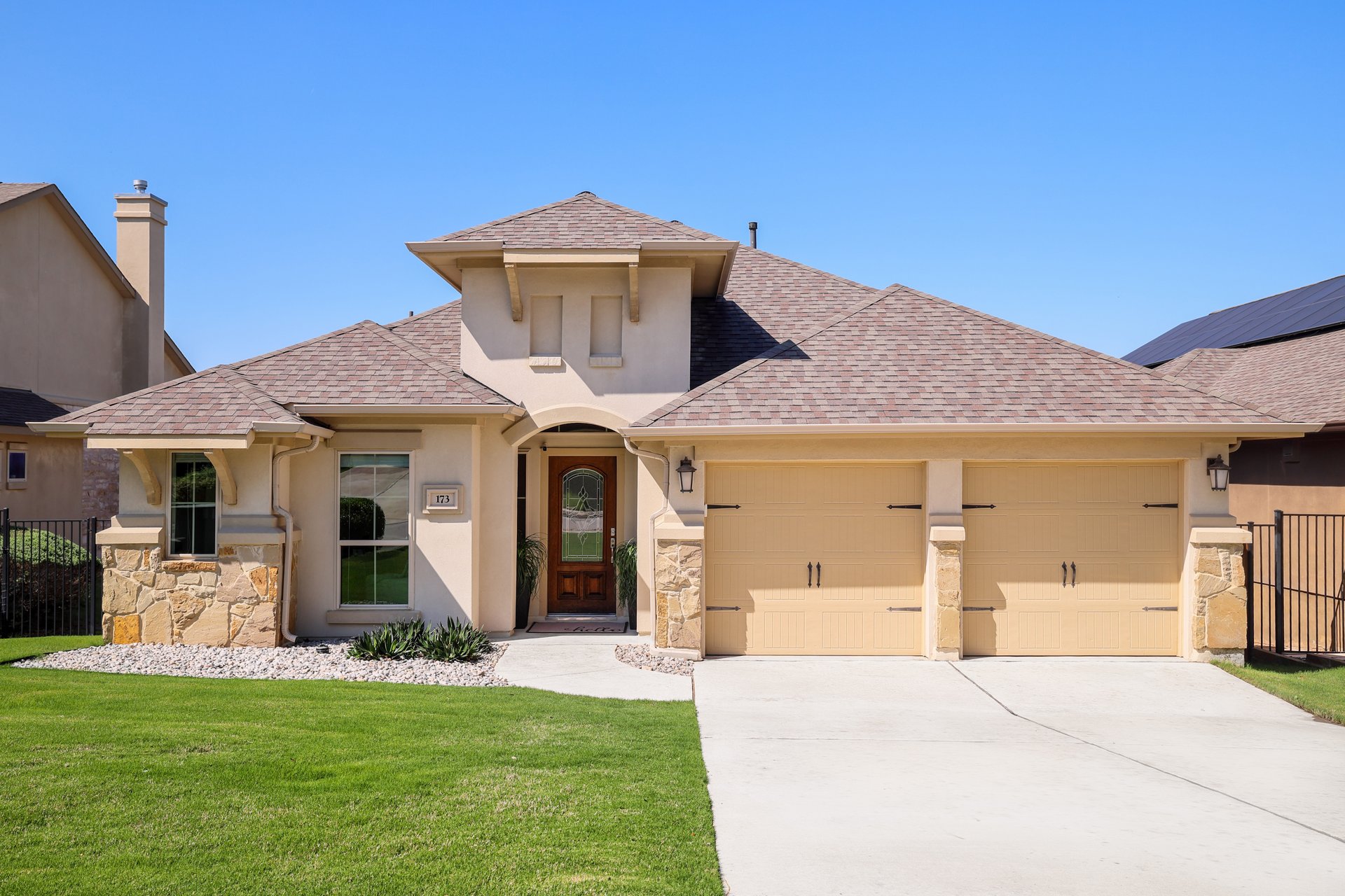 173 Santa Maria Street Georgetown, TX 78628 - Photo 9 of 39 Stucco and stone facade with a decorative wood-panel entry door, arched portico, and a two-car garage
