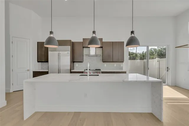 a large white kitchen with kitchen island a sink a counter and a refrigerator