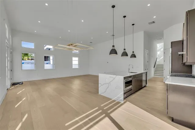 a view of a kitchen with kitchen island a sink stainless steel appliances and cabinets