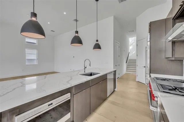 a kitchen with stainless steel appliances a sink a stove and a wooden floors