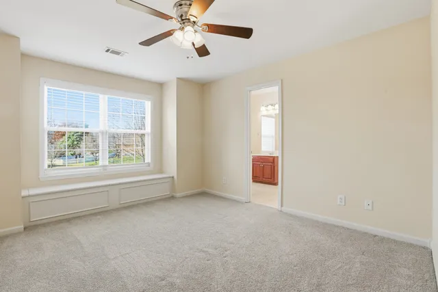an empty room with windows and fan