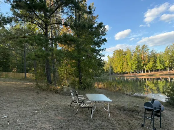 a view of a lake with a table and chairs under an umbrella