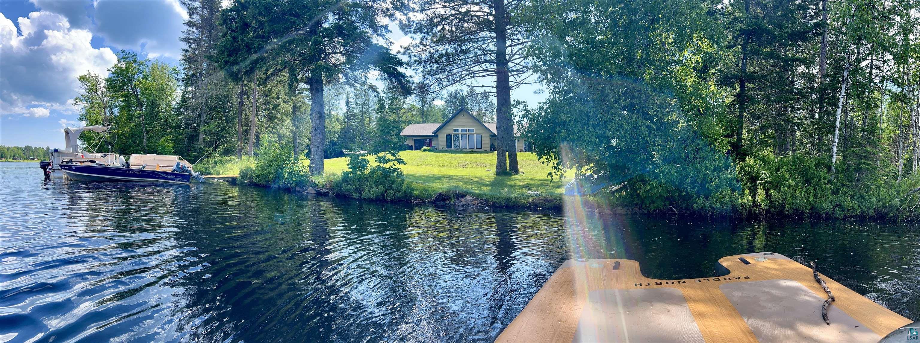 5274 Marble Lake Road Two Harbors, MN 55616 - Photo 68 of 79 Waterside property featuring a single-story residence with a light-toned exterior, a sloped roofline, and multiple windows facing the water