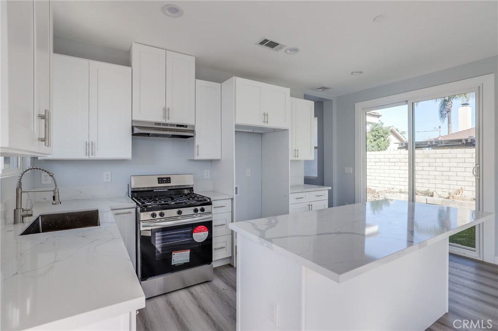 11875 Wisteria Avenue, Unit ADU Fountain Valley, CA 92708 - Photo 5 of 14 a kitchen with stainless steel appliances a stove a sink a refrigerator white cabinets and wooden floor