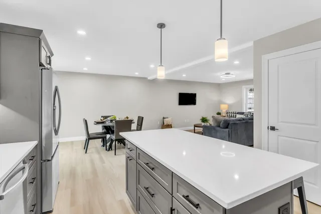 a kitchen with stainless steel appliances a stove a sink a kitchen island with chairs and wooden floor